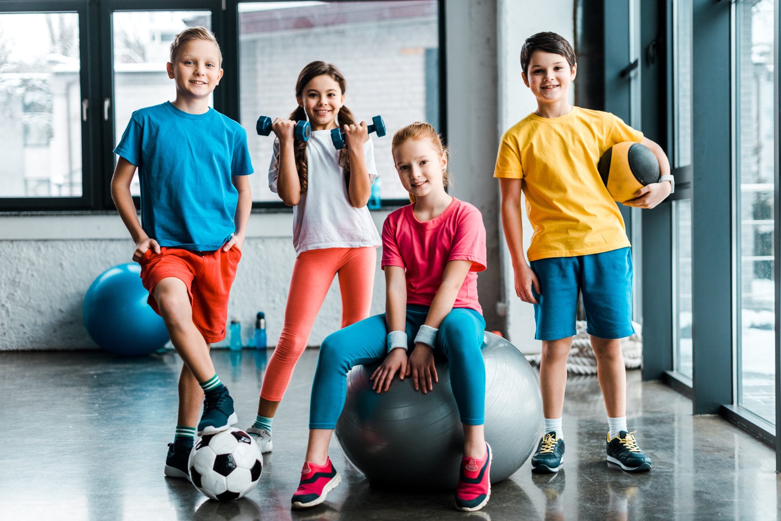 laughing preteen kids posing with sport equipment